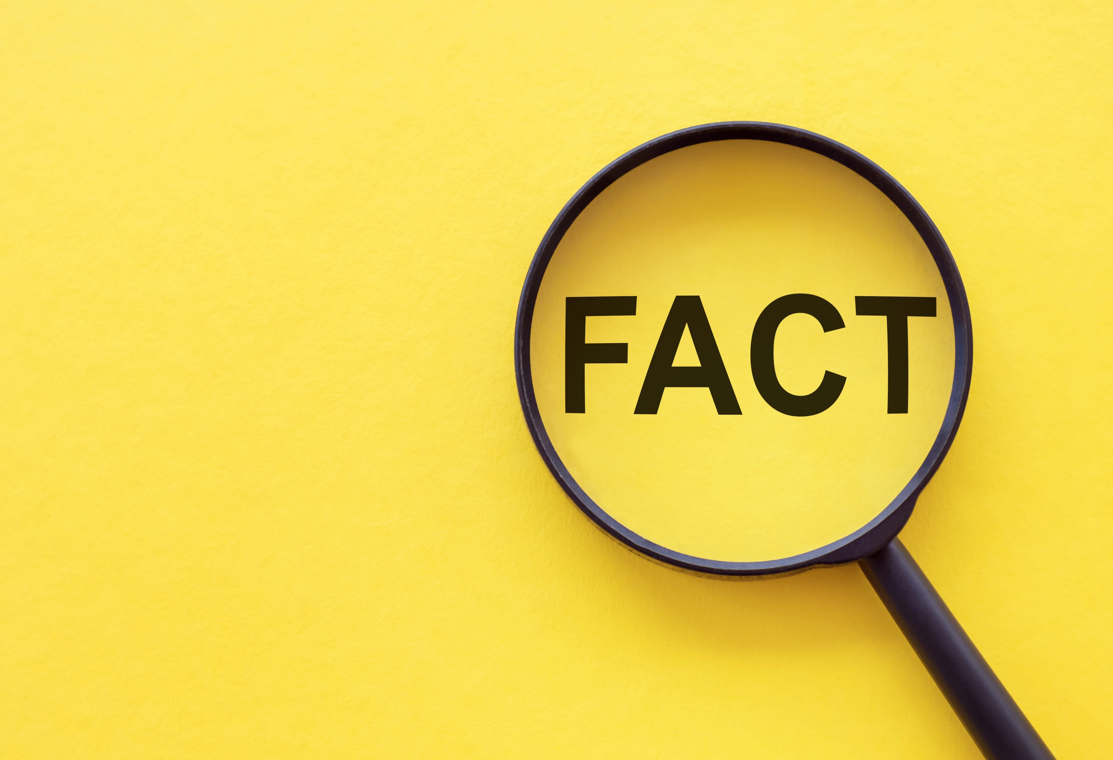 Fact,-,Word,Through,Magnifying,Glass,On,Yellow,Table
